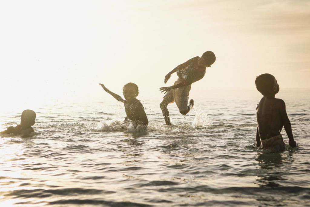 ילדים משחקים בחדווה בים. חופש בתוך פעילויות